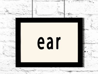 Siyah ahşap çerçeve, beyaz tuğla duvarda yazılı kulak. 