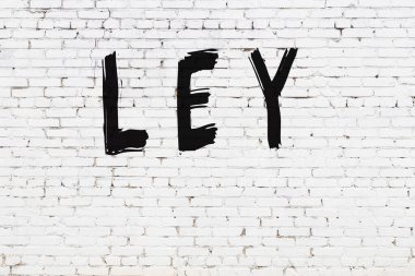 Yazıt ley beyaz duvara siyah boya ile yazılmış..