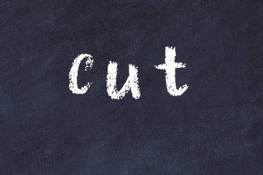 Tebeşir el yazısıyla yazılmış yazı siyah masaya kesilmiş.