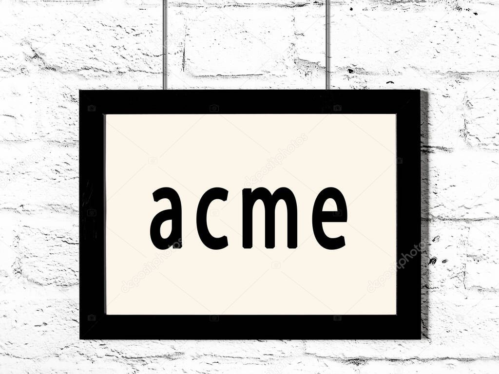 Black wooden frame with inscription acme hanging on white brick wall 