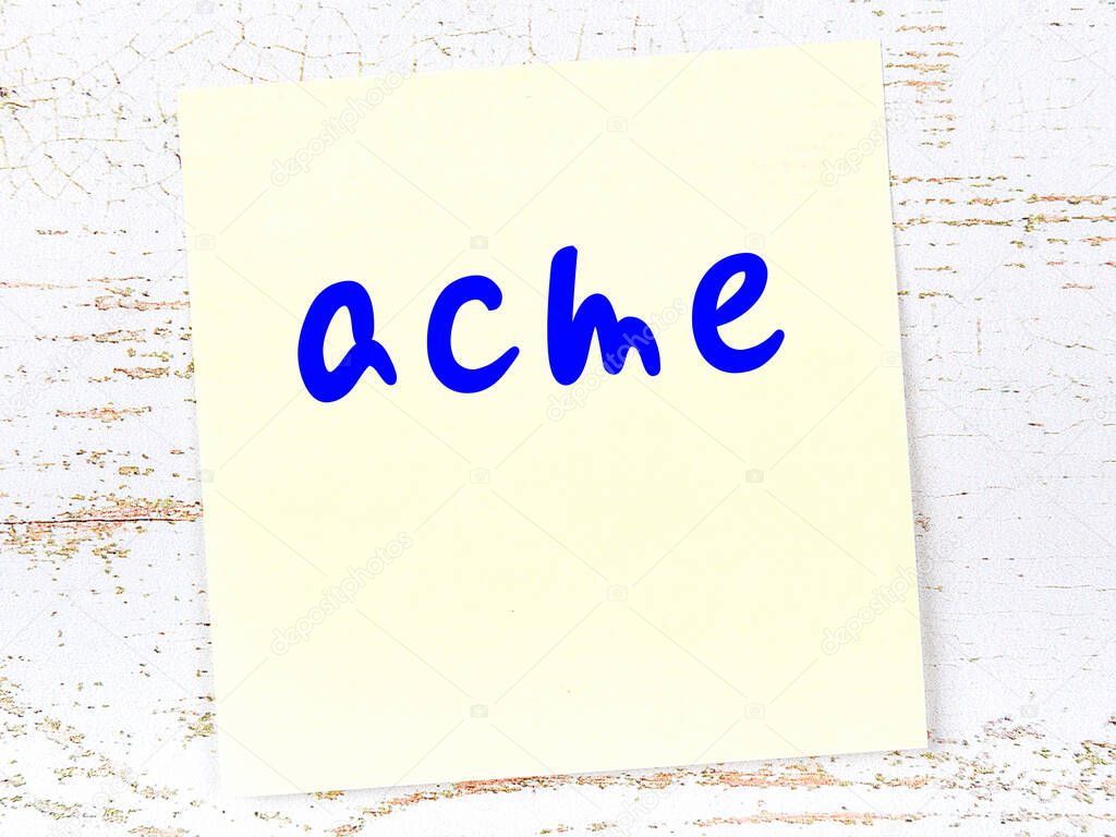 Yellow sticky note on wooden wall with handwritten inscription acme