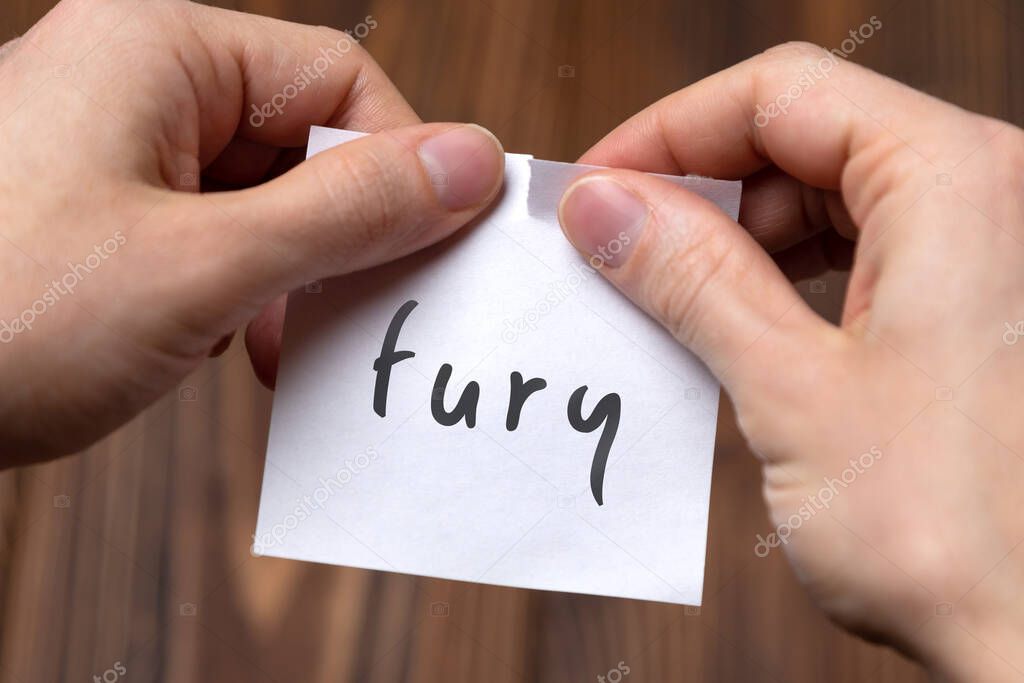 Cancelling fury. Hands tearing of a paper with handwritten inscription.