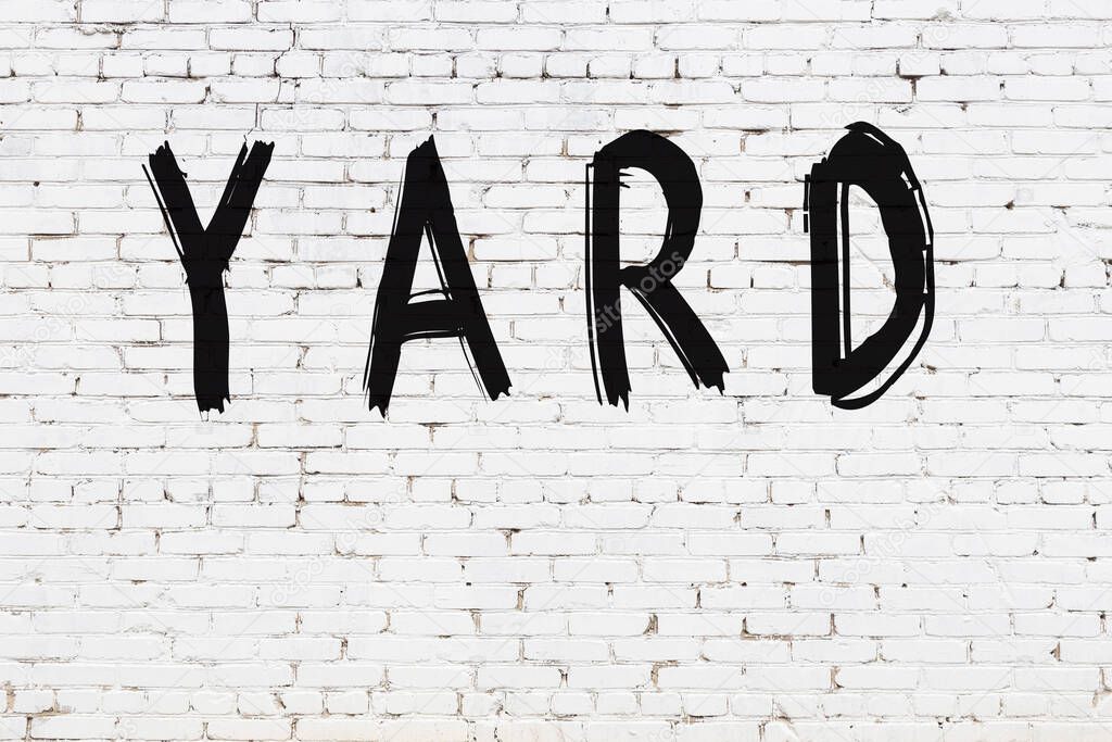 White brick wall with inscription yard handwritten with black paint