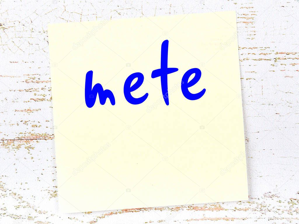 Concept of reminder about mete. Yellow sticky sheet of paper on wooden wall with inscription