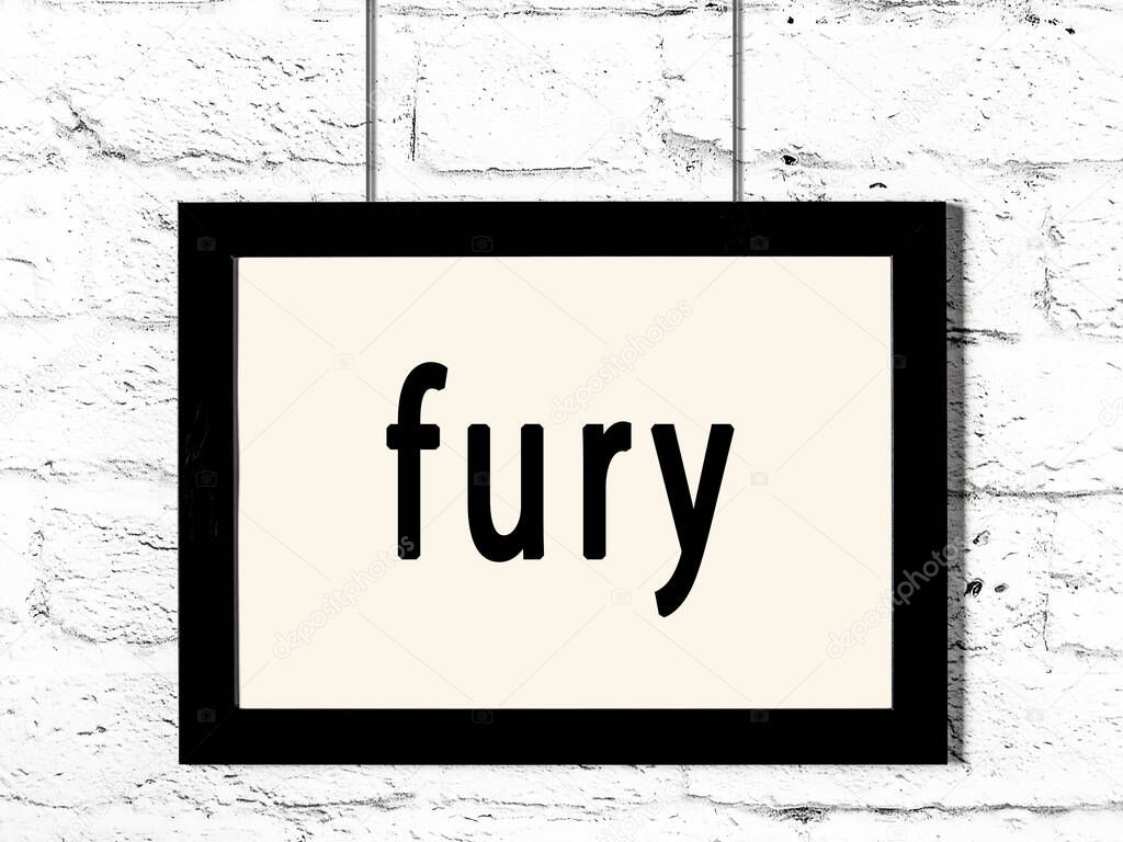 Black wooden frame with inscription fury hanging on white brick wall 