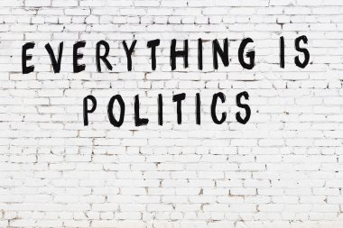 Beyaz tuğla duvara zekice alıntılar yazılı siyah bir yazı.