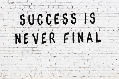 Beyaz tuğla duvar ve bilgece alıntıların yazılı olduğu siyah yazı.