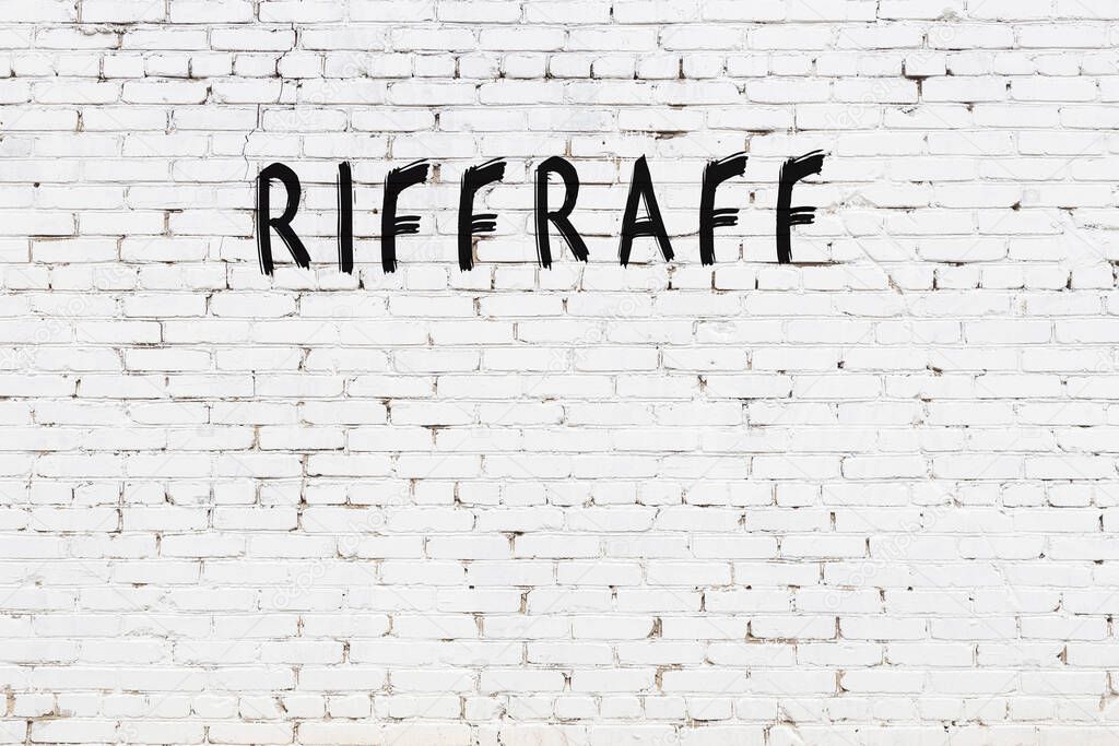 White brick wall with inscription riffraff handwritten with black paint