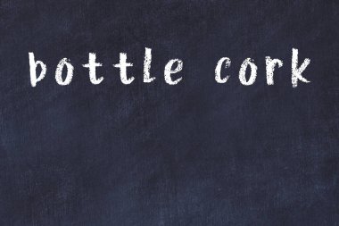 Tebeşir elle yazılmış yazı mantarı siyah masanın üstünde.