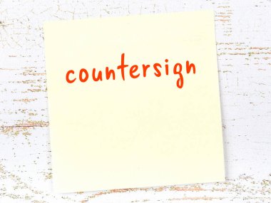 Tahta duvarda el yazısıyla yazılmış tezgah işareti olan sarı yapışkan bir not.