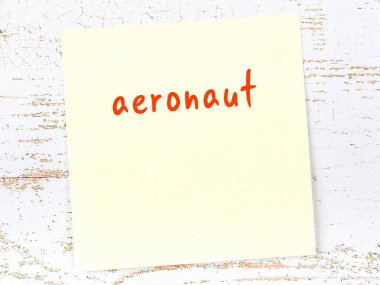 Aeronaut 'u hatırlatma kavramı. Tahta duvarda üzerinde yazı olan sarı yapışkan kağıt.