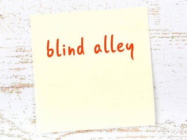 Tahta duvardaki sarı yapışkan notta el yazısıyla yazılmış çıkmaz sokak yazısı var.