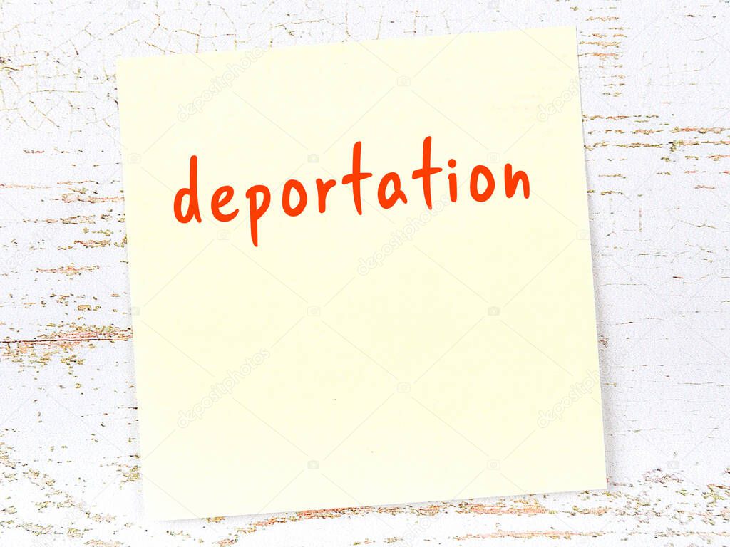 Concept of reminder about deportation. Yellow sticky sheet of paper on wooden wall with inscription