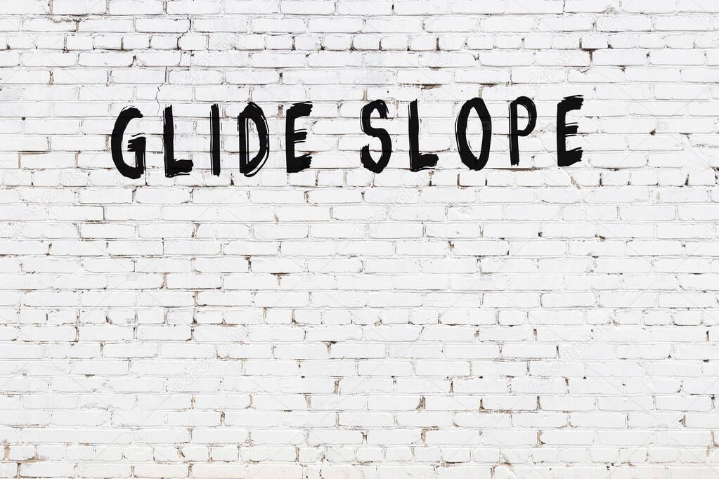 Inscription glide slope written with black paint on white brick wall.
