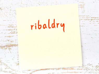 Tahta duvardaki sarı yapışkan notta el yazısıyla yazılmış müstehcen yazılar var.