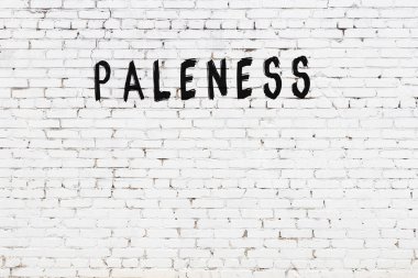 Beyaz tuğlalı duvar. Yazılı solgunluk. Siyah boyayla yazılmış.