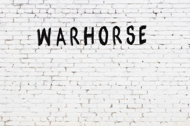 Siyah boyalı el yazısıyla yazılmış savaş atı yazılı beyaz tuğla duvar.