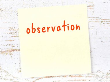 Tahta duvardaki sarı yapışkan notta elle yazılmış gözlem yazısı var.