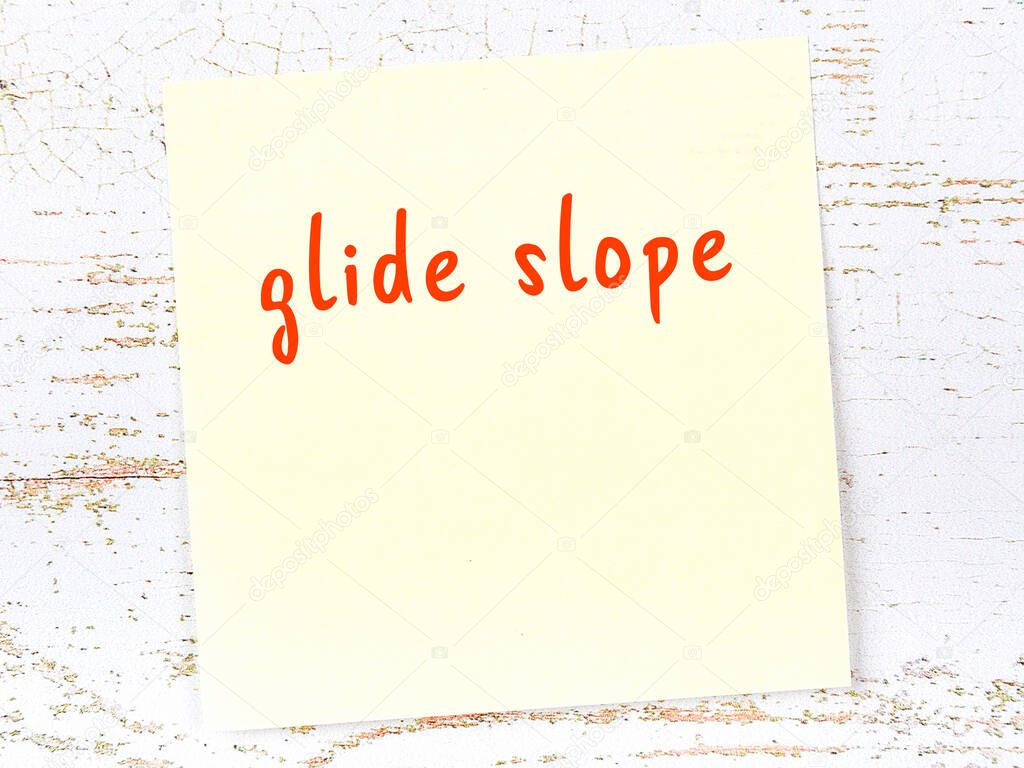 Yellow sticky note on wooden wall with handwritten inscription glide slope