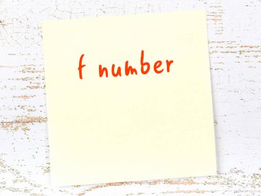 Hatırlatma konsepti f sayısı. Tahta duvarda üzerinde yazı olan sarı yapışkan kağıt.