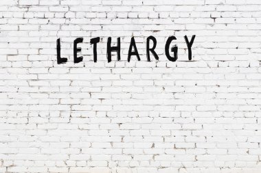 Yazı uyuşukluğu beyaz tuğla duvara siyah boya ile yazılmış..