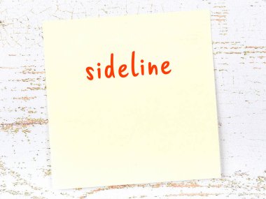 Tahta duvarda el yazısıyla yazılmış sarı yapışkan bir not var.