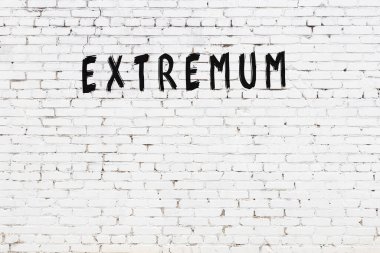 Beyaz tuğlalı duvar, üzerinde siyah boya ile yazılmış ekstrem yazı var.