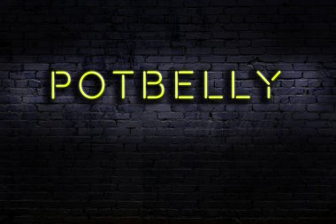 Tuğla duvara yaslanmış göbekli neon tabela. Gece görünümü