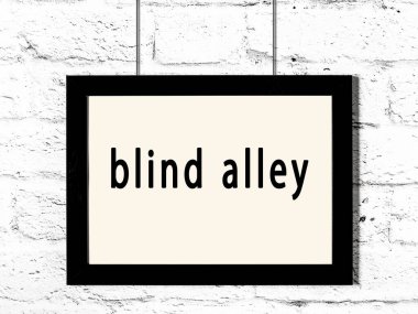 Siyah ahşap çerçeve ve beyaz tuğla duvarda asılı kör sokak yazıları. 