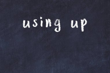 Tebeşir el yazısıyla yazılmış yazıyı siyah masaya yapıştırarak.