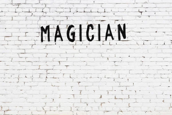 白いレンガの壁に黒い塗料で書かれた碑文魔術師 — ストック写真