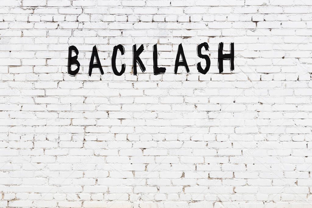 Inscription backlash written with black paint on white brick wall.