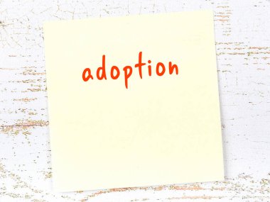Evlat edinmeyi hatırlatma kavramı. Tahta duvarda üzerinde yazı olan sarı yapışkan kağıt.