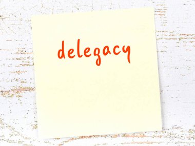 Tahta duvardaki sarı yapışkan notta el yazısıyla yazılmış delegeler var.