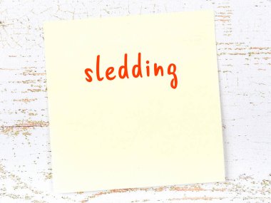 Tahta duvardaki sarı yapışkan notta el yazısıyla yazılmış kızak izi var.