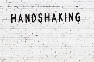 Beyaz tuğla duvara siyah boya ile yazılmış el sıkışma..