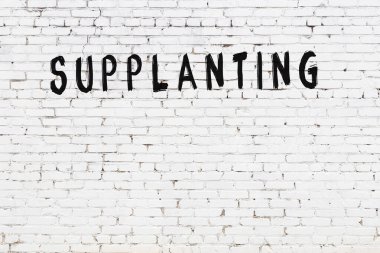 Üzerinde yazı olan beyaz tuğla duvar. Siyah boyayla el yazısıyla değiştirilmiş.