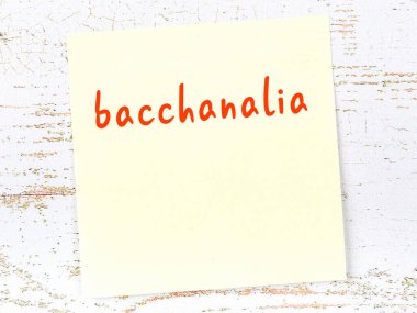 Tahta duvardaki sarı yapışkan notta el yazısıyla yazılmış Bacchanalia.
