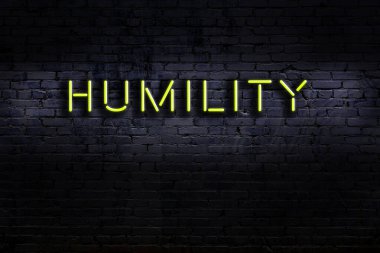 Duvara karşı alçak gönüllülük yazılı neon levhası. Gece görünümü