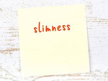 Zayıflığı hatırlatma kavramı. Tahta duvarda üzerinde yazı olan sarı yapışkan kağıt.