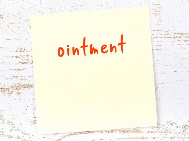 Tahta duvarda el yazısıyla yazılmış merhem ile sarı yapışkan bir not var.