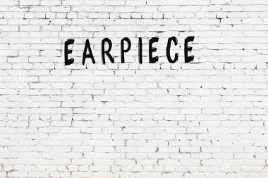 Siyah boyalı el yazısıyla yazması kulaklık olan beyaz tuğla bir duvar.