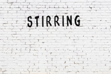 Yazı, beyaz tuğla duvara siyah boya ile yazılmış..