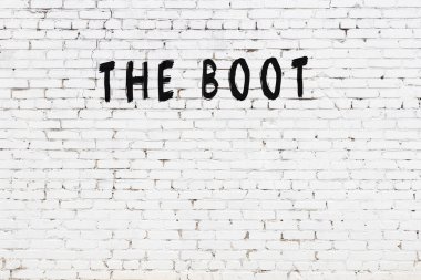 Üzerinde yazı olan beyaz tuğla duvar. Siyah boyayla yazılmış çizme.