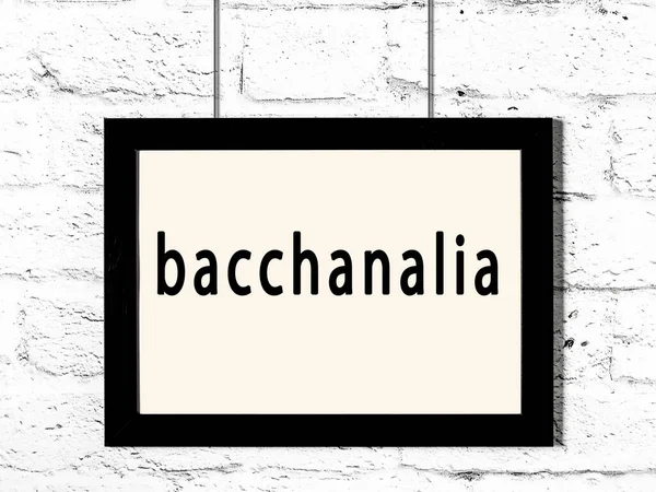 白いレンガの壁にかかって碑文Bacchanaliaと黒い木製のフレーム — ストック写真