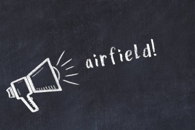 Hoparlörün tebeşir çizimi ve siyah masanın üzerine el yazısıyla yazılmış hava alanı.