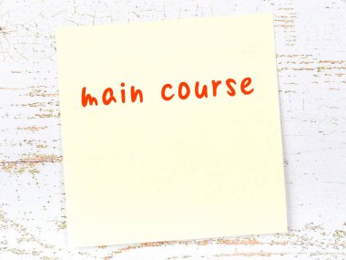 Ana yemekle ilgili hatırlatma kavramı. Tahta duvarda üzerinde yazı olan sarı yapışkan kağıt.