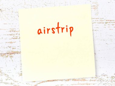 Uçak pistini hatırlatma kavramı. Tahta duvarda üzerinde yazı olan sarı yapışkan kağıt.