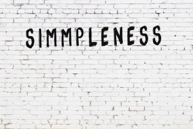 Beyaz tuğlalı duvar, siyah boyayla yazılmış.