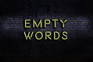 Üzerinde tuğla duvara karşı boş kelimeler yazan neon tabela. Gece görünümü